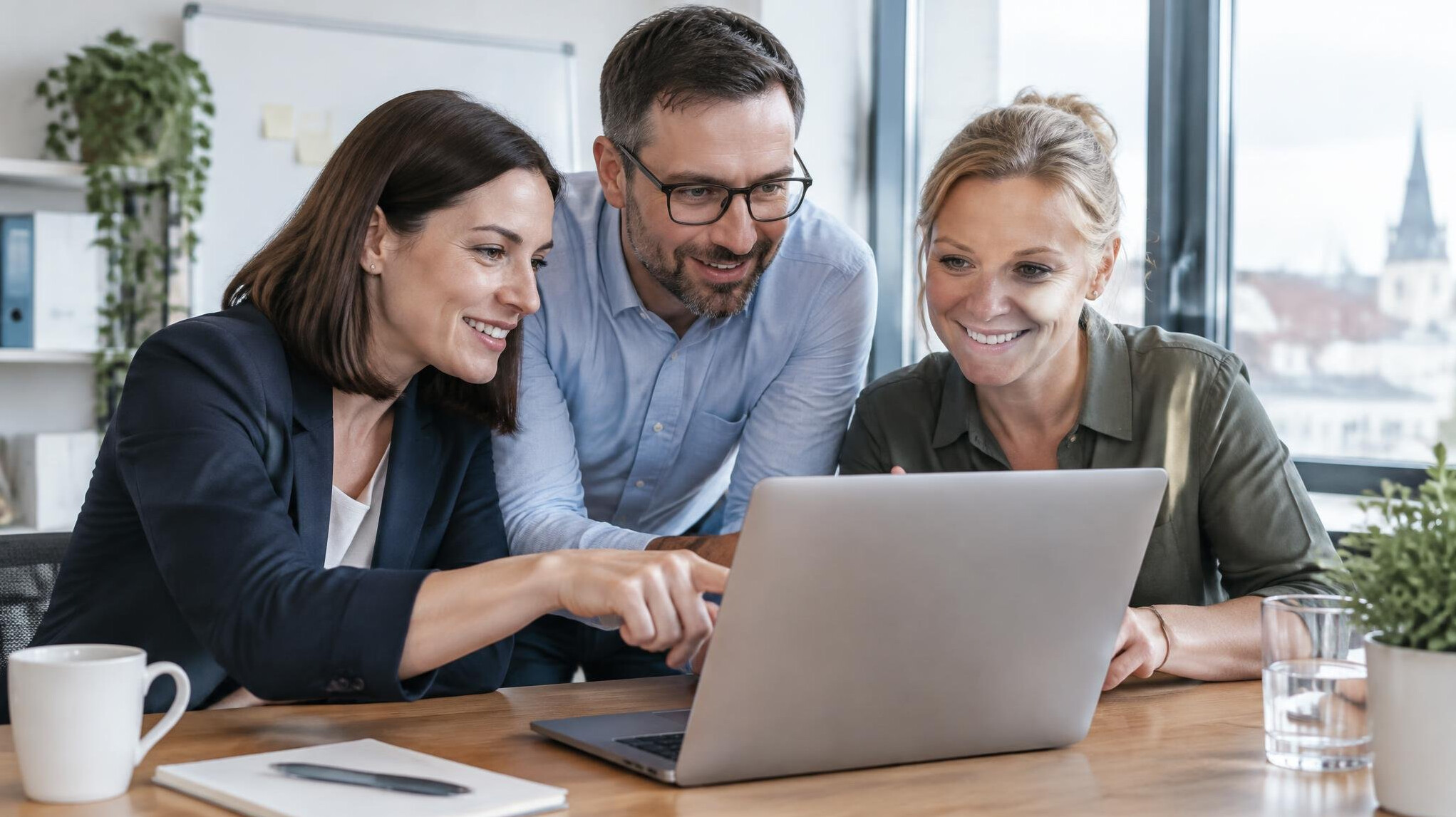 Small team of professionals collaborating around a laptop